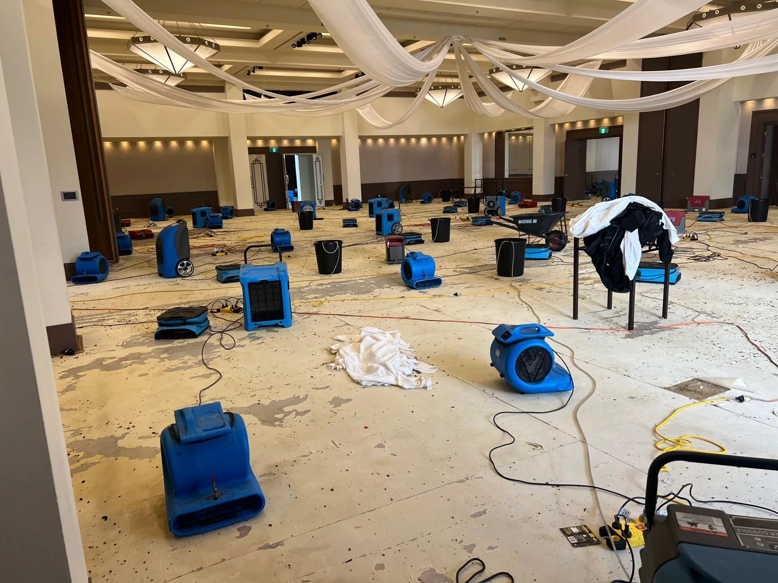 Air movers and drying equipment arranged across a large room