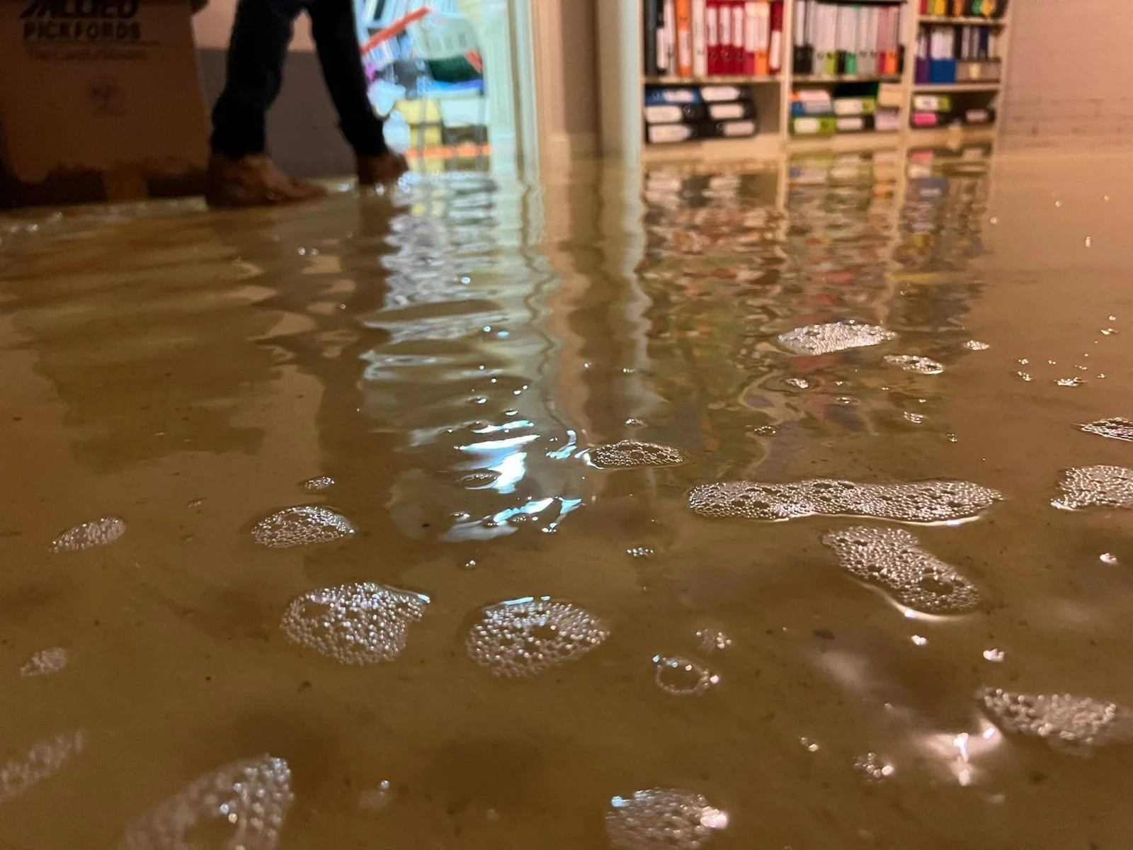 Floodwater spreading across a tiled indoor floor