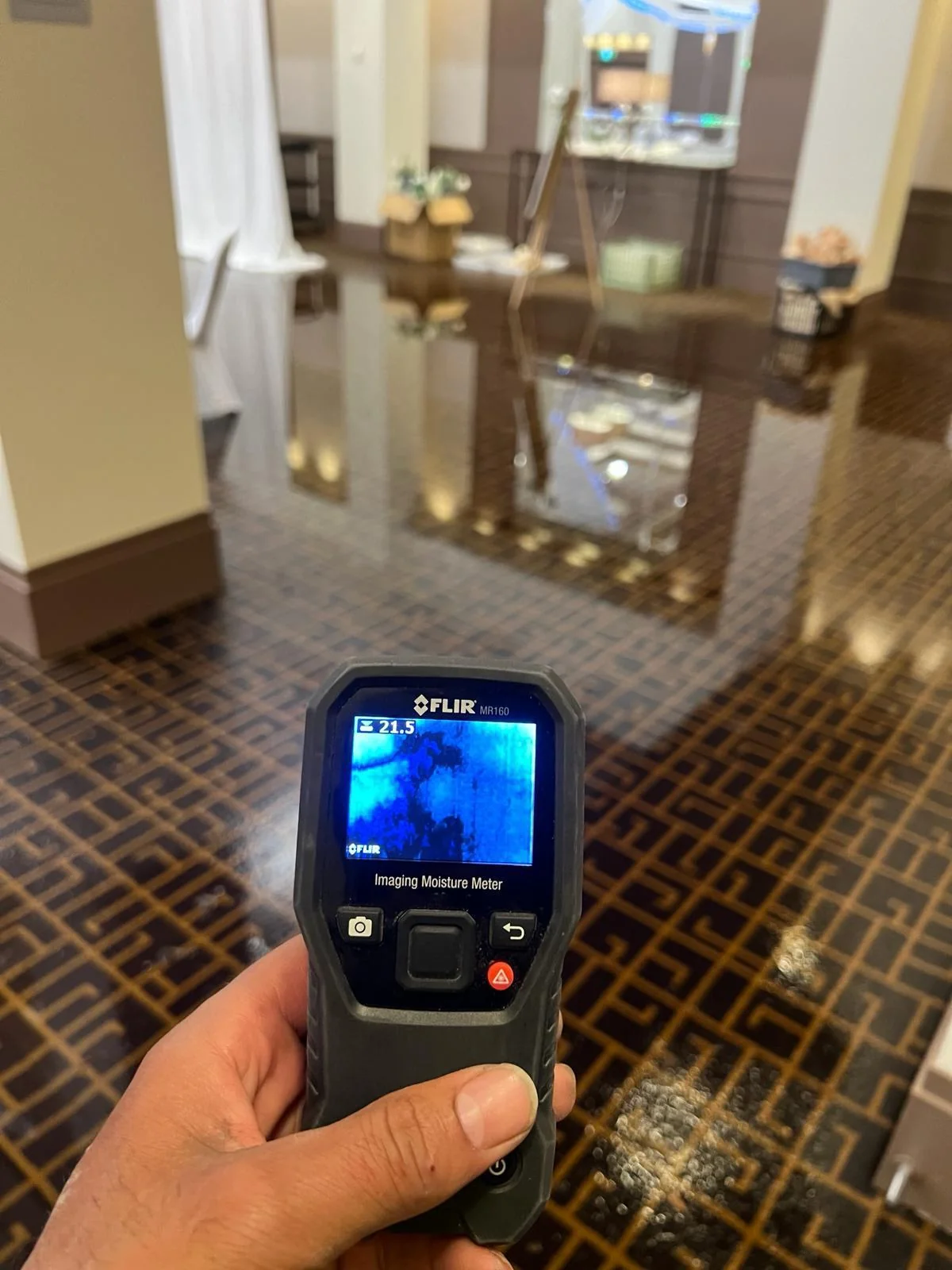 Moisture meter checking water damage on a wet floor