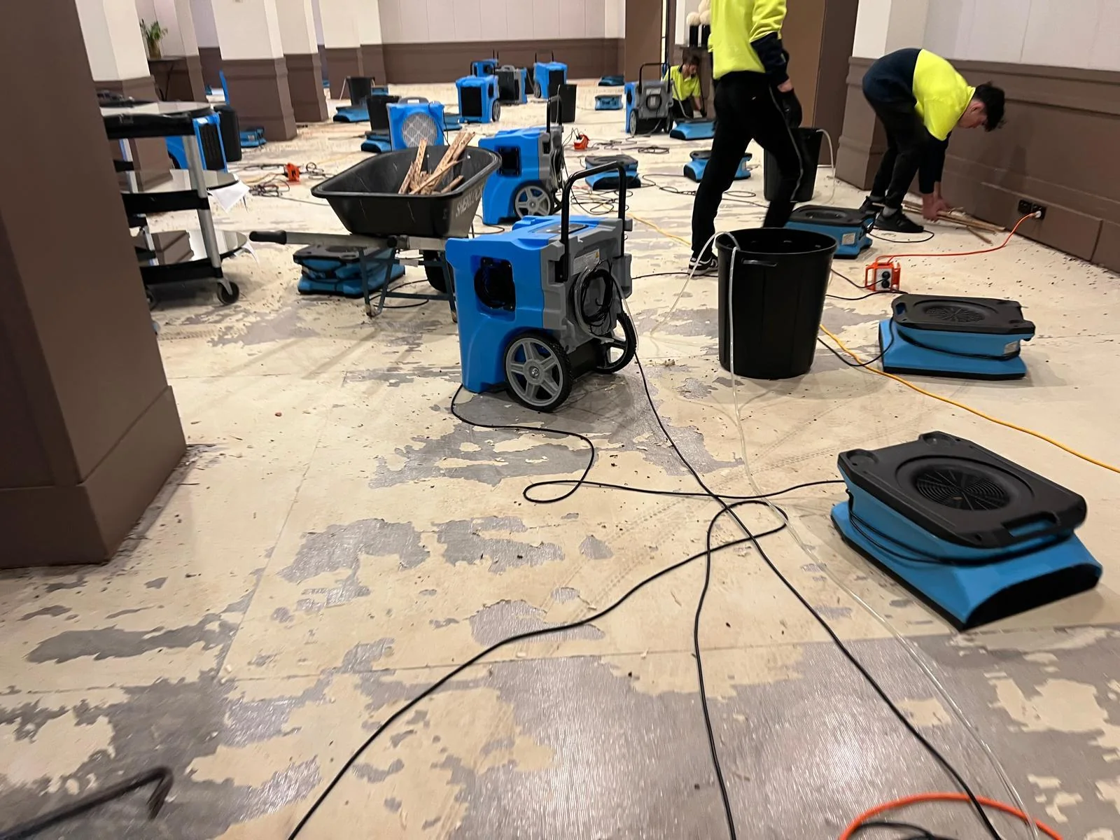 Restoration team working with drying equipment inside a water-damaged property